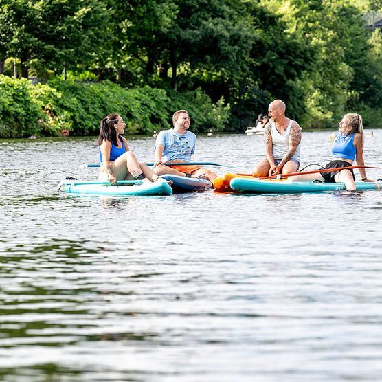 Freunde sitzen auf SUPs im Sommer am Stadthafen Mülheim