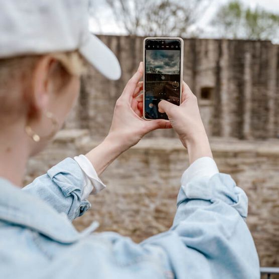 Frau mit Smartphone im Frühjahr auf dem Erlebnispfad im Schloß Broich