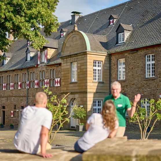 Paar und Tourguide auf Stadtführung im Sommer im Innenhof von Schloß Broich