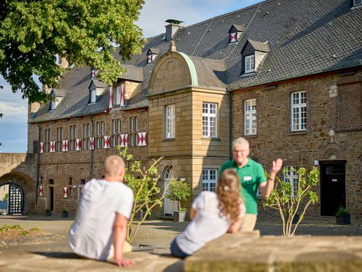 Paar und Tourguide auf Stadtführung im Sommer im Innenhof von Schloß Broich