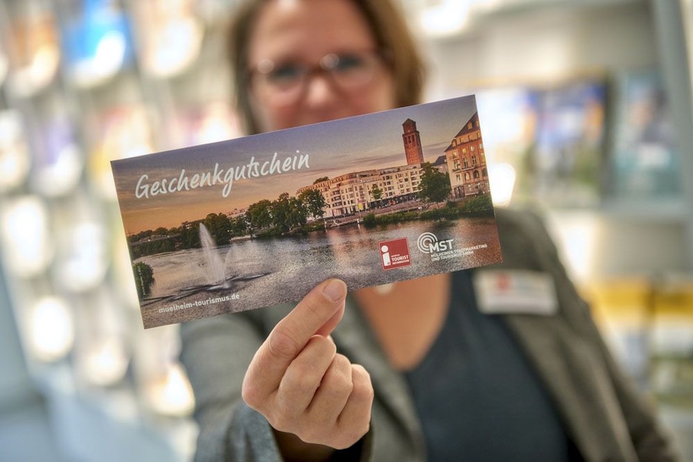 Frau hält Geschenkgutschein für die Touristinfo Mülheim an der Ruhr